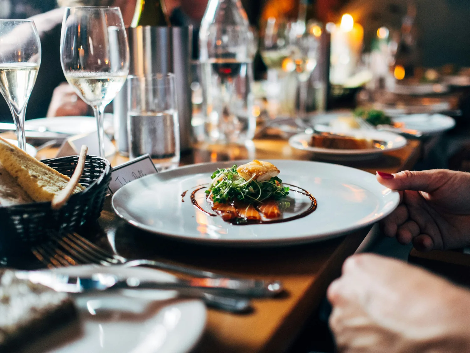 A plated course served at a candlelit table set with wine glasses and bread