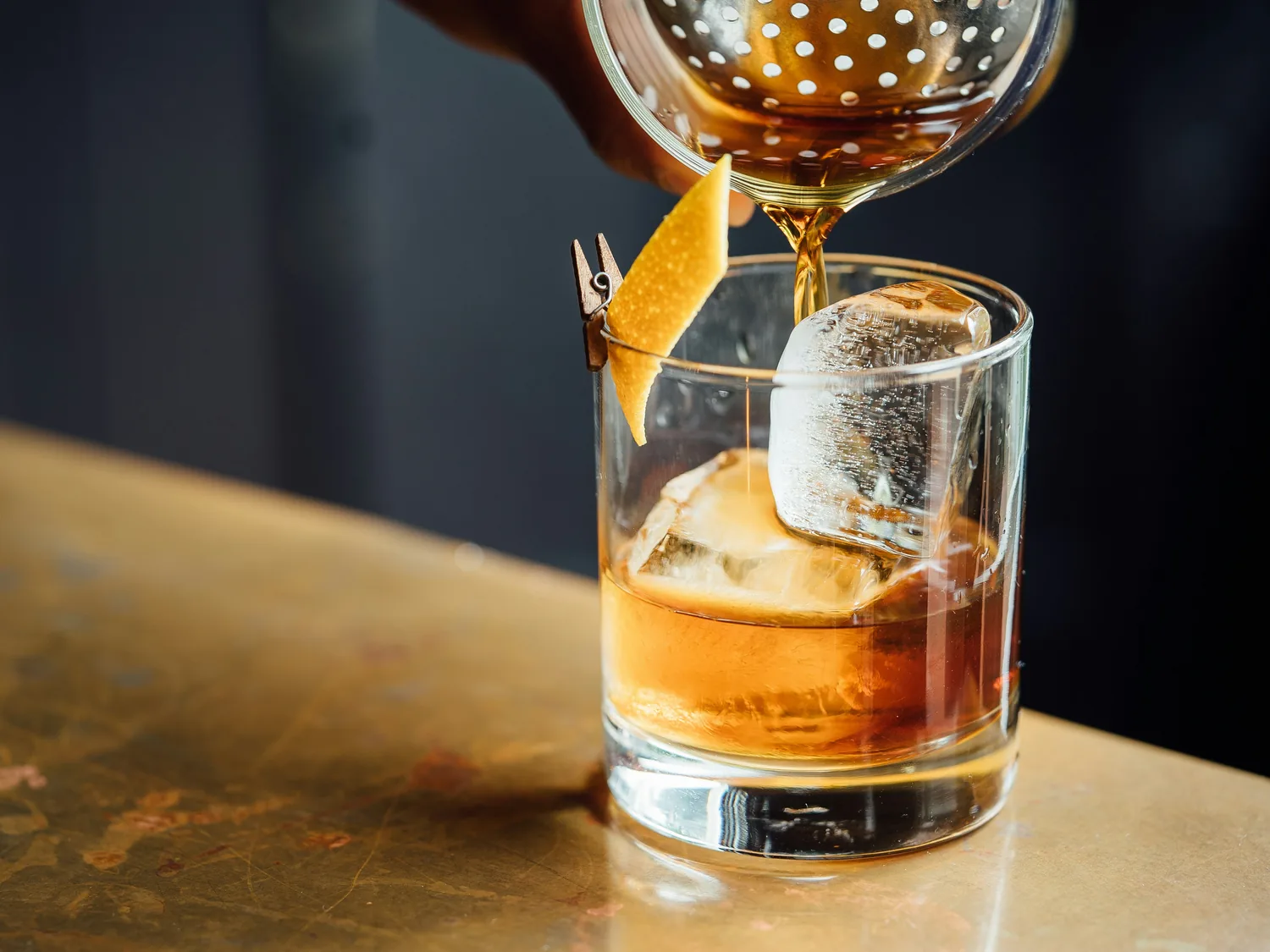 An old fashioned poured over ice with an orange twist at the bar
